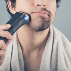 Young man shaving half of his beard